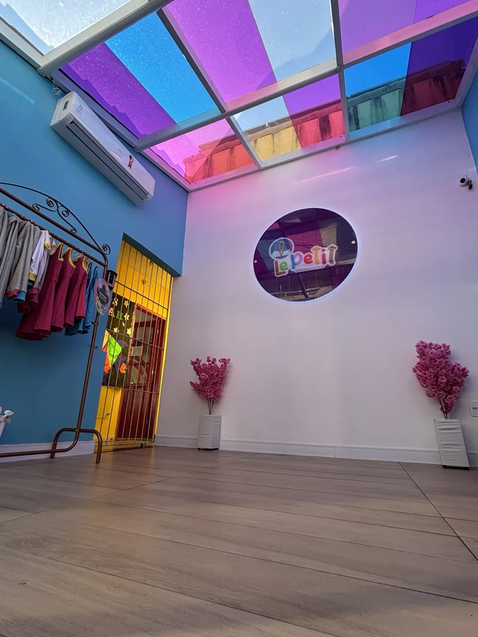 Área interna de entrada da Le Petit com cobertura colorida e logotipo da escola