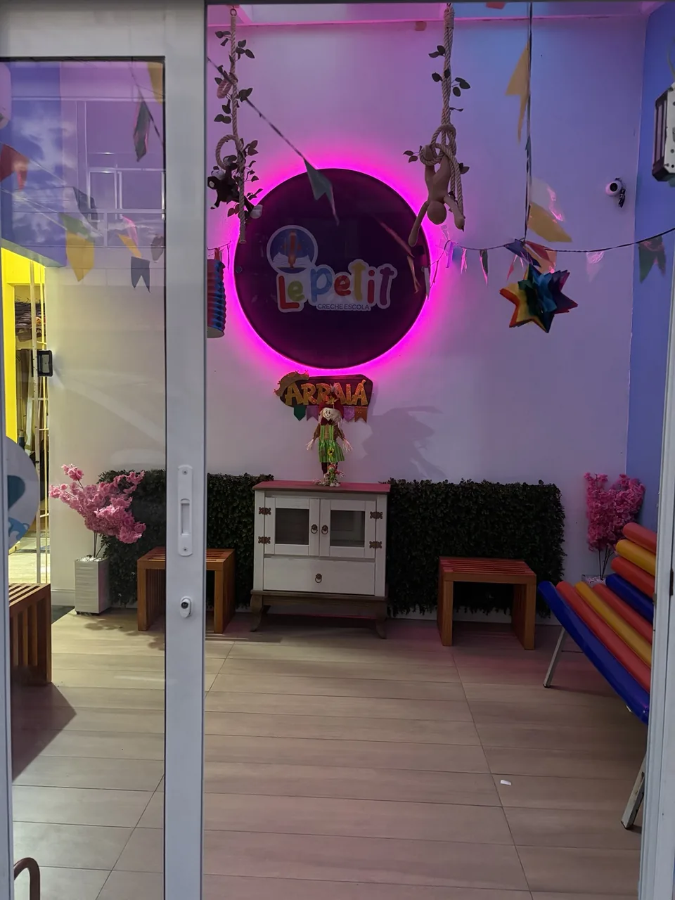 Entrada da Le Petit vista pela porta de vidro, com logotipo iluminado